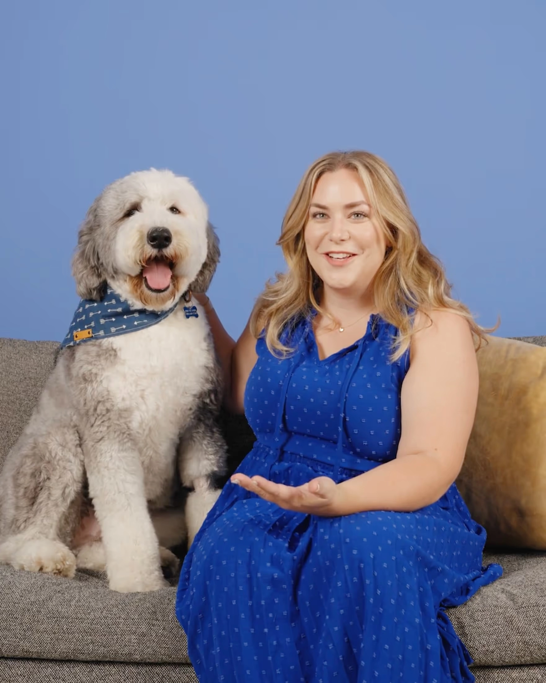 Meghan with Carl, a shaggy gray and white dog, on a sofa against a blue wall