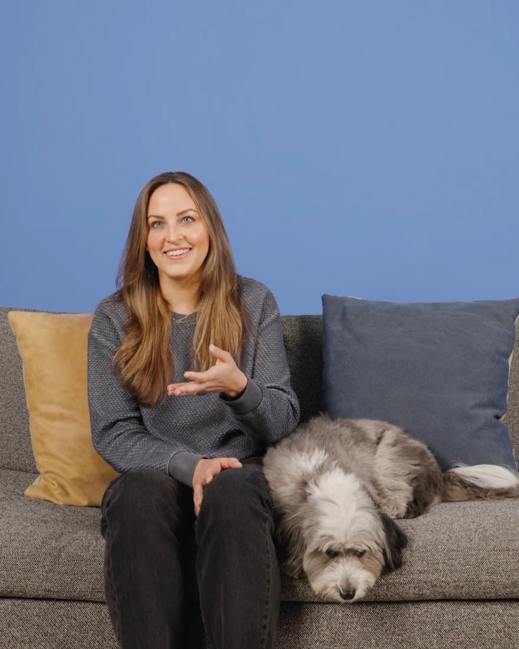 Lindsey on a sofa with Archer, a gray and white dog, against a blue wall
