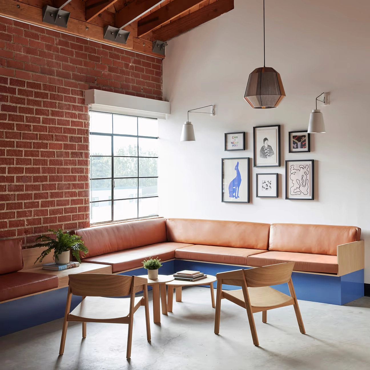 A modernanimal clinic lobby with a brick wall, framed art, a pendant lamp and a tan leather bench
