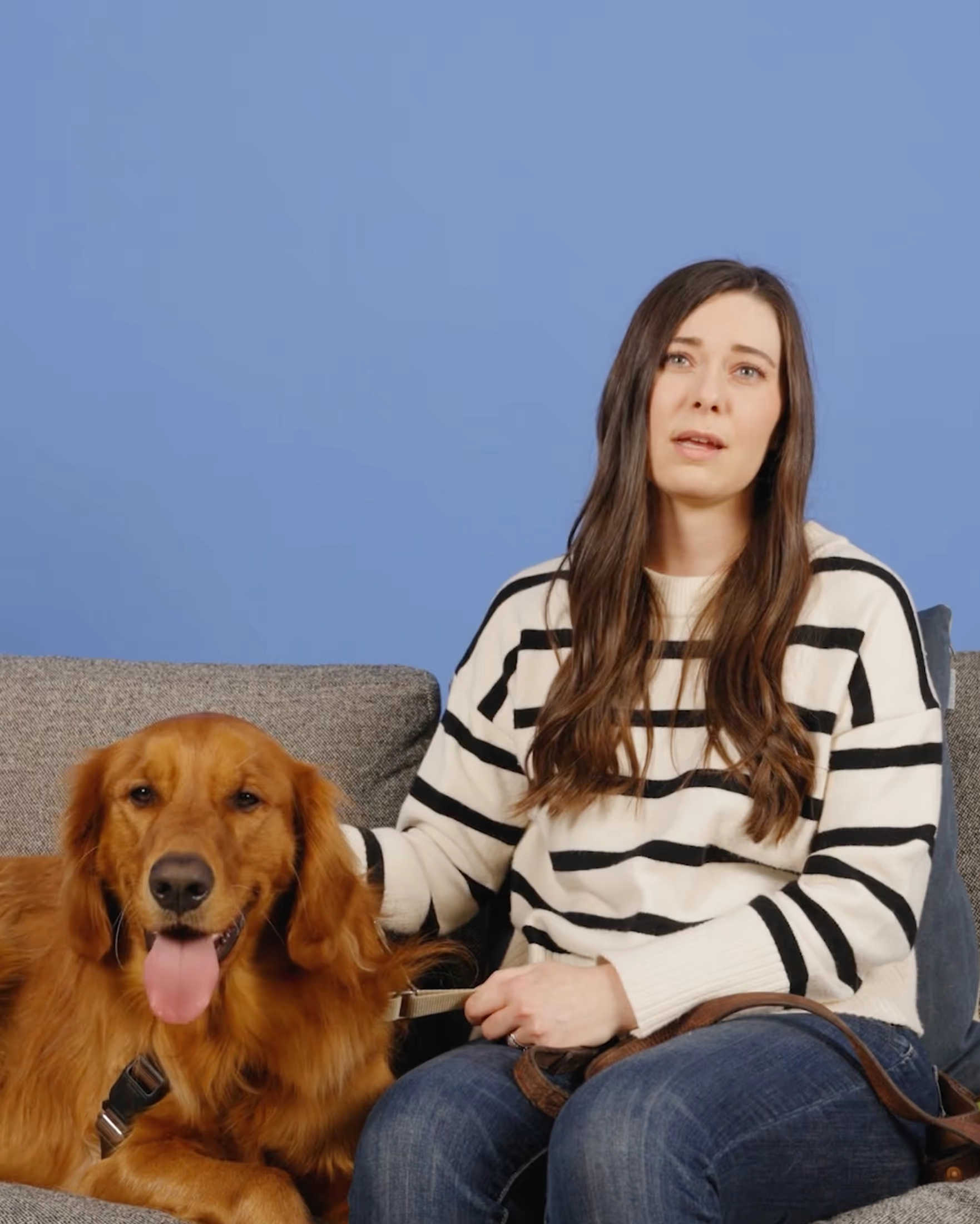 A woman in a striped sweater beside a golden retriever on a sofa