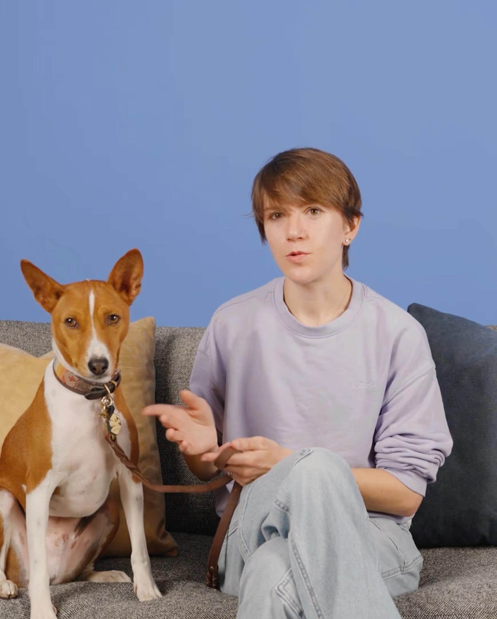A teenager beside a tan and white dog on a sofa